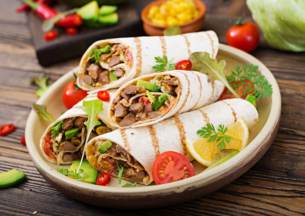 Burrito τυλίγει με μοσχάρι και λαχανικά σε ένα ξύλινο υπόβαθρο. Βόειο κρέας burrito, μεξικάνικο φαγητό. Υγιεινά τρόφιμα φόντο. Μεξικάνικη κουζίνα. - Φωτογραφία, εικόνα
