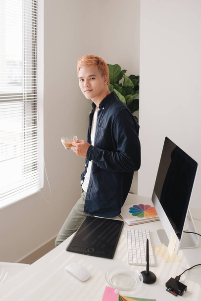Αρσενικό δημιουργική εργαζόμενος στέκεται μπροστά στο δημιουργικό γραφείο - Φωτογραφία, εικόνα