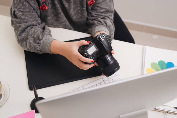 Жінка-фотограф працює за столом в сучасному офісі
 - Фото, зображення