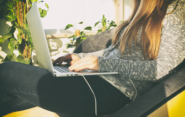 Молода жінка сидить на дивані і працює в ноутбуці
 - Фото, зображення