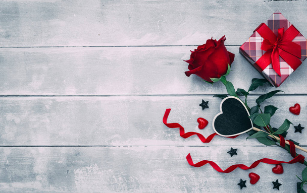 Valentine background with red rose flower and small present box on rustic wood. Happy lovers day gift mockup, copy space - Foto, imagen