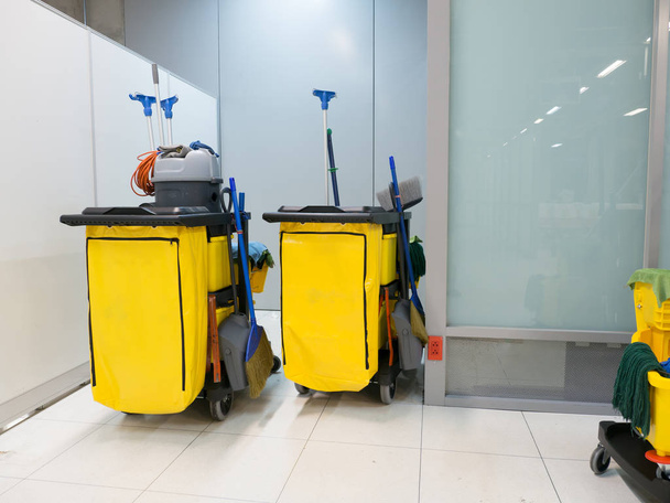 Cleaning Cart in the station. Cleaning tools cart and Yellow mop bucket wait for cleaning.Bucket and set of cleaning equipment in the airport office. - Photo, Image