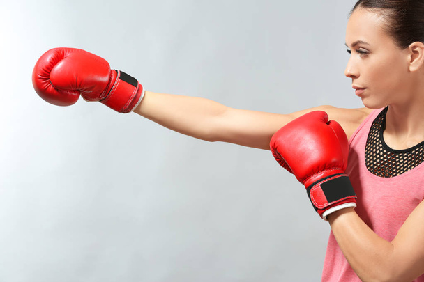 Strong woman in boxing gloves on grey background - Fotó, kép