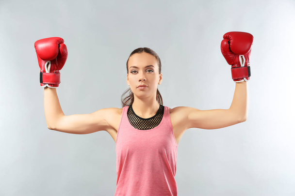 Strong woman in boxing gloves on grey background - Fotografie, Obrázek