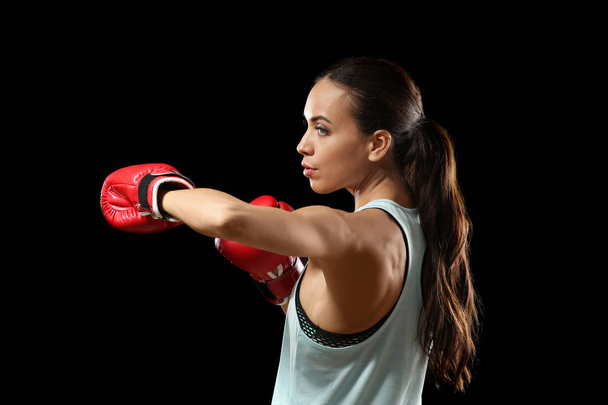 Strong woman in boxing gloves on black background - Φωτογραφία, εικόνα