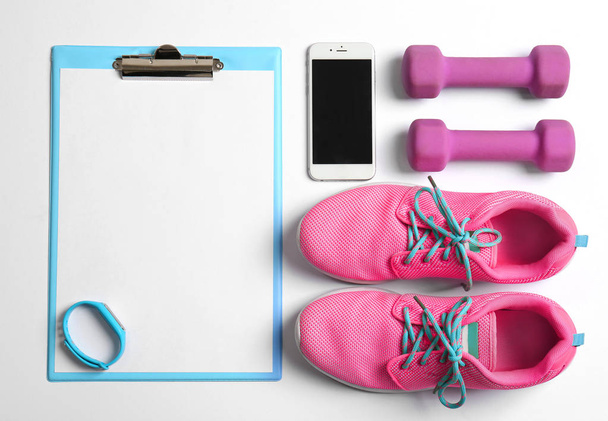 Clipboard with blank paper for exercise plan, gym stuff and mobile phone on white background. Flat lay composition - Fotografie, Obrázek