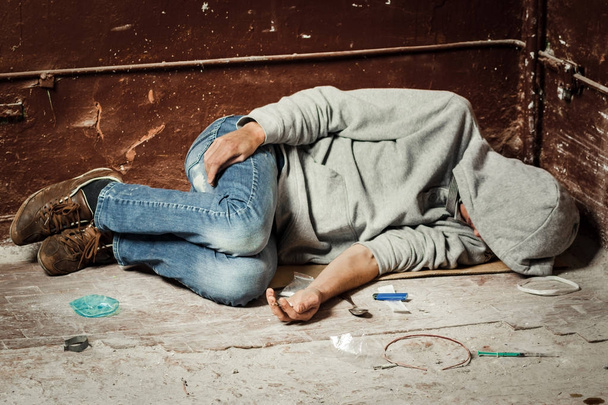 A man is a drug addict with a syringe using drugs lying on the f - Valokuva, kuva