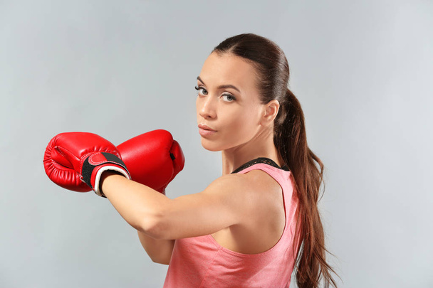 Strong woman in boxing gloves on grey background - Foto, afbeelding