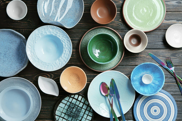 Ceramic tableware and cutlery on wooden background, top view - Fotó, kép