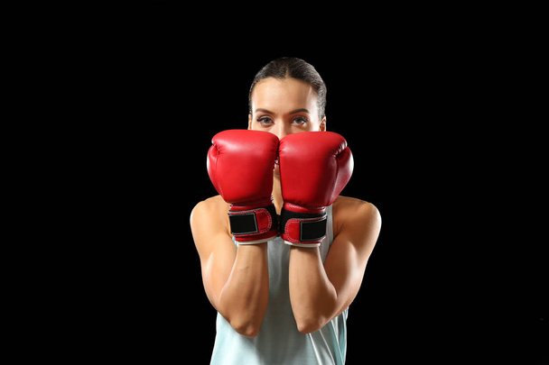 Strong woman in boxing gloves on black background - 写真・画像