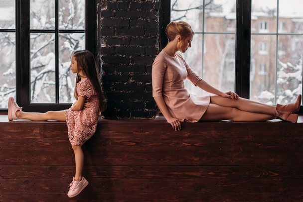 depressed mother and daughter sitting on windowsills back to back - Photo, Image