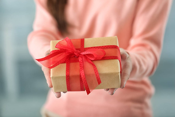 Young woman holding gift box at home, closeup - Foto, Imagen