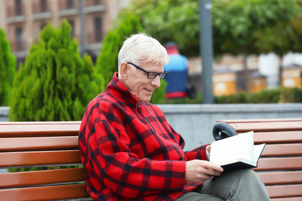 Красивый взрослый мужчина с ноутбуком на скамейке на открытом воздухе
 - Фото, изображение
