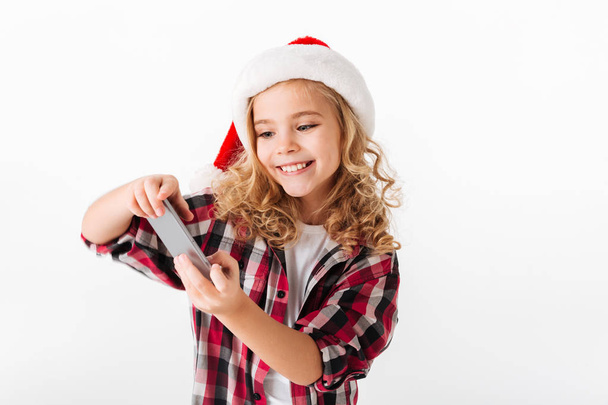 Portrait of a smiling little girl dressed in christmas hat - Foto, Imagen
