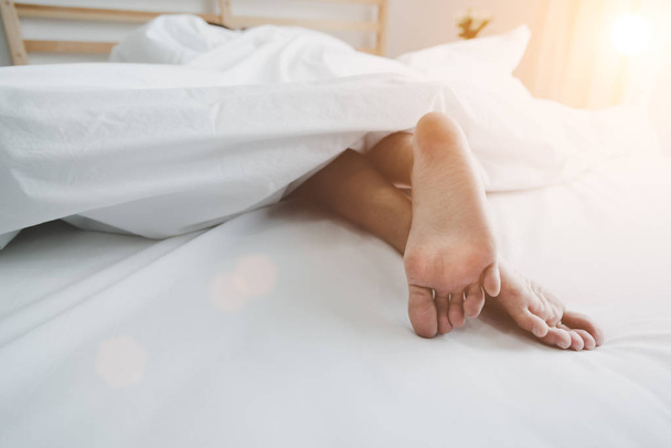 Blote voeten van menselijke op bed in de ochtend. Single en werk mensen concept. Luie dag en geluk home thema. - Foto, afbeelding
