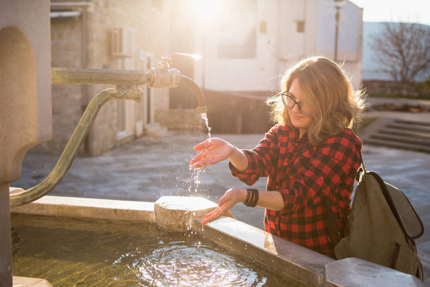 Traveler girl in the old town. Medieval water tap in the square of the European town. - Photo, image