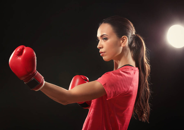 Strong woman in boxing gloves on black background - Fotoğraf, Görsel