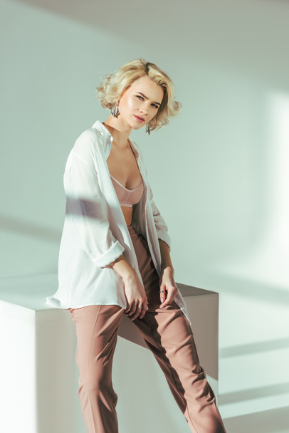 beautiful charming blonde girl in bra, shirt and pants looking at camera in studio - Fotografie, Obrázek