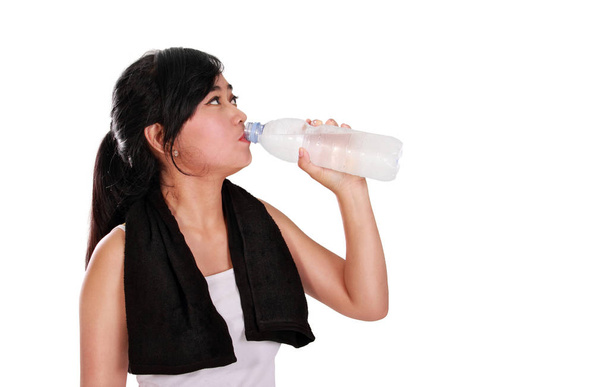 Lekkoatletka picia butelka wody mineralnej, na białym tle nad czarno-białych przestrzeni - Zdjęcie, obraz