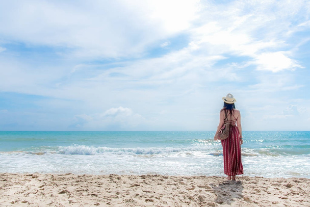 Summer Day.  Smiling woman wearing fashion summer standing and see the sandy ocean beach. Happy woman enjoy and relax vacation.  Lifestyle and Travel Concept. - Fotó, kép