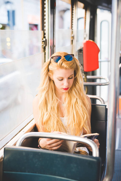 Jonge mooie vrouw in de stad reizen per bus lezen boek - Foto, afbeelding