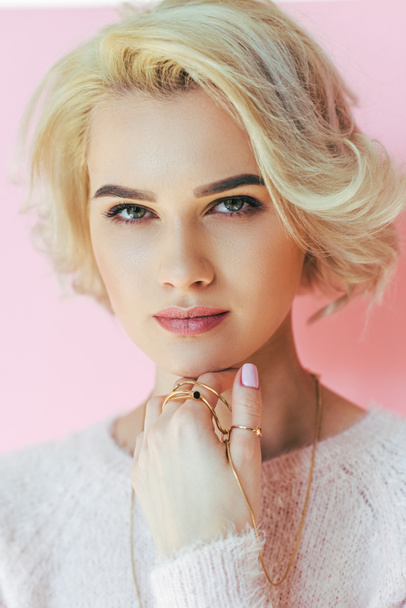 portrait of beautiful blonde girl with jewelry looking at camera isolated on pink - Фото, зображення