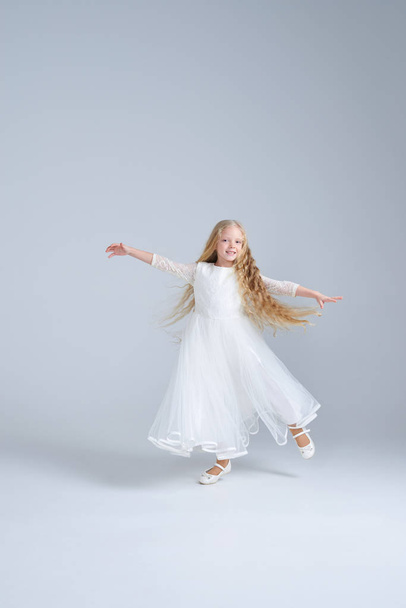 Cute blonde girl in white dress dancing at studio - Fotoğraf, Görsel