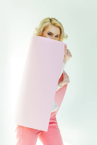 beautiful blonde woman holding pink placard and looking at camera on grey  - Φωτογραφία, εικόνα