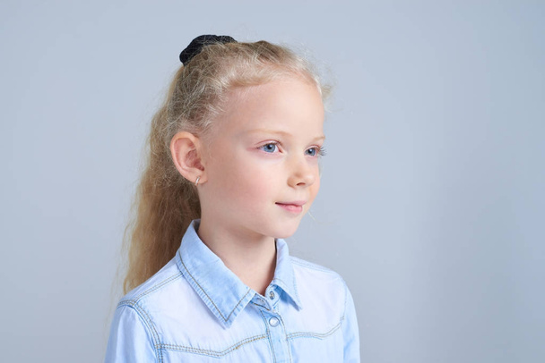 hübsches kleines Mädchen mit blauen Augen posiert im Studio - Foto, Bild