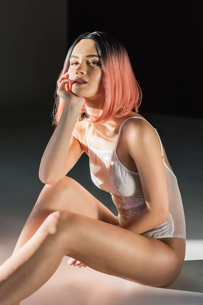 sensual woman with pink hair posing in white lace bodysuit - 写真・画像