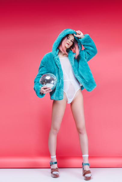 fashionable girl posing in blue fur coat with disco ball on pink - Photo, Image