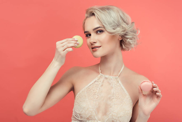 beautiful blonde woman with two delicious macarons, isolated on red - Foto, Imagem