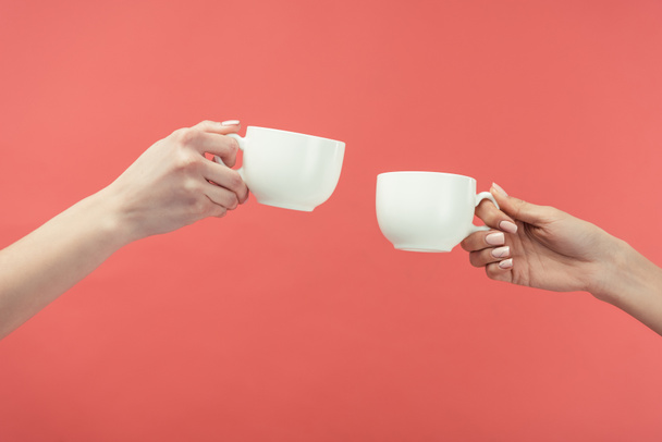 cropped view of women holding tea cups, isolated on red - Photo, Image