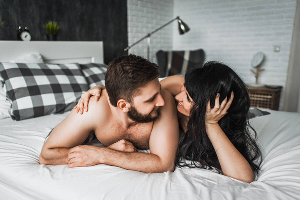 Guy and girl hugging in bed. Guy and girl have sex. Couple in love in bed. Wedding night. Make love. Lovers in bed. The relationship between a man and a Woman. Sex between a man and a woman - Фото, зображення
