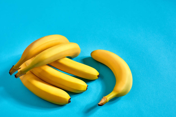 Fresh bananas close up on bright blue background. Flat lay. Summer concept. - Foto, afbeelding