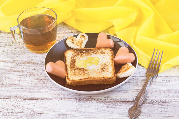 Frühstück zur Feier des Valentinstages mit Wurst und Eiern im Brot herzförmig - Foto, Bild