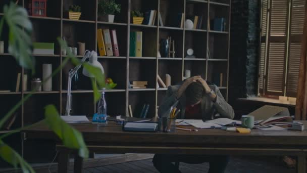 Frustrated businessman putting head on desk in home office. Tired businessman - Materiał filmowy, wideo