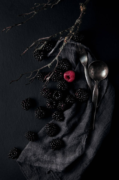 monochrome food picture of blackberries and one red raspberry on a napkin and slate plate kitchen table can be used as background - Fotoğraf, Görsel