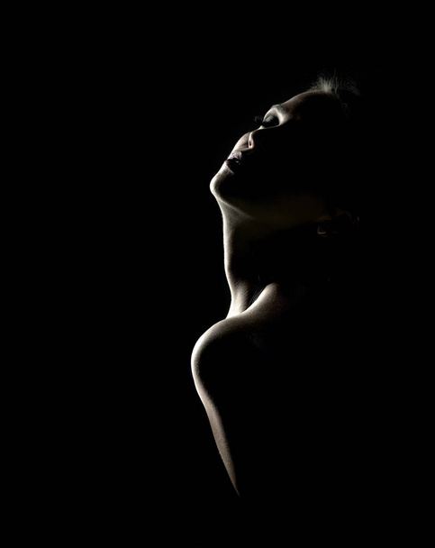 Sensual portrait of a woman in shadow on a dark background - Fotoğraf, Görsel