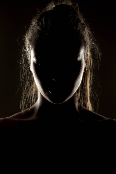 Μυστηριώδες πορτρέτο μιας γυναίκας στη σκιά σε σκούρο φόντο - Φωτογραφία, εικόνα