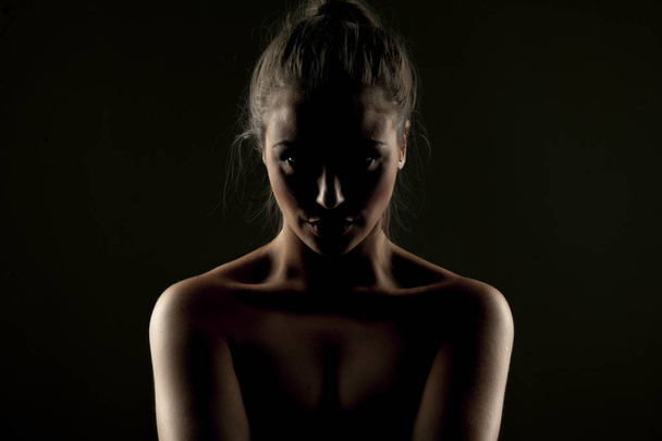 Μυστηριώδες πορτρέτο μιας γυναίκας στη σκιά σε σκούρο φόντο - Φωτογραφία, εικόνα