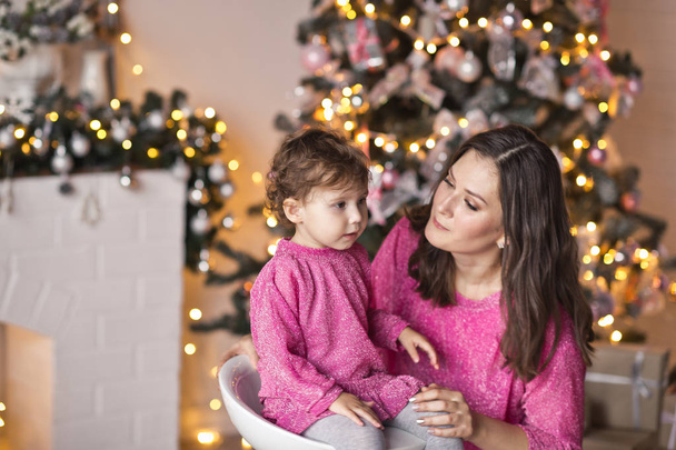 The little girl next to her mother, surrounded by Christmas ligh - Фото, изображение