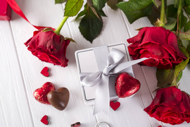 Rose rosse fresche e confezione regalo su tavola di legno
 - Foto, immagini
