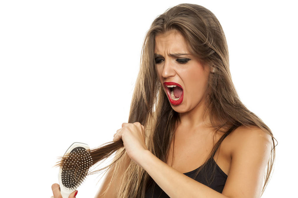 Ideges gyönyörű nő birtoklás egy probléma-val fésülködés a haját - Fotó, kép