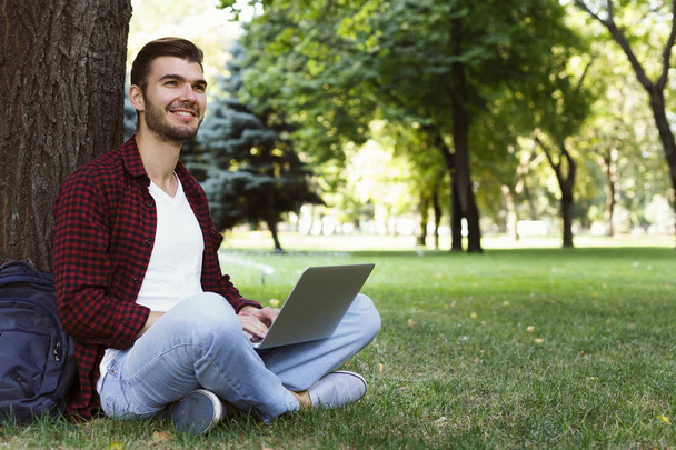 Homme assis sur l'herbe avec ordinateur portable à l'extérieur
 - Photo, image