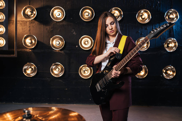 θηλυκό κιθαρίστας παίζει bas κιθάρα, ροκ συγκρότημα, σκηνή με τα φώτα στο παρασκήνιο - Φωτογραφία, εικόνα
