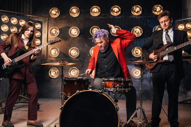 τους μουσικούς στα κοστούμια επί σκηνής με φώτα, ρετρό στυλ, κιθαρίστες και ντράμερ ροκ μπάντα - Φωτογραφία, εικόνα
