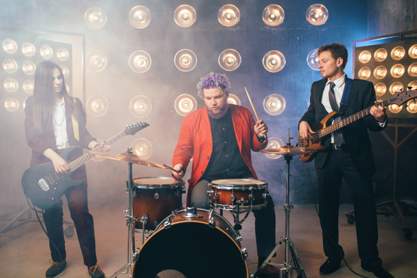 musicians in suits on stage with lights, retro style, guitarists and drummer, rock band - Photo, Image