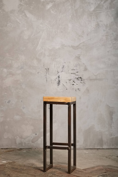 High metal bar chair with wooden seat near grunge concrete wall - Фото, изображение