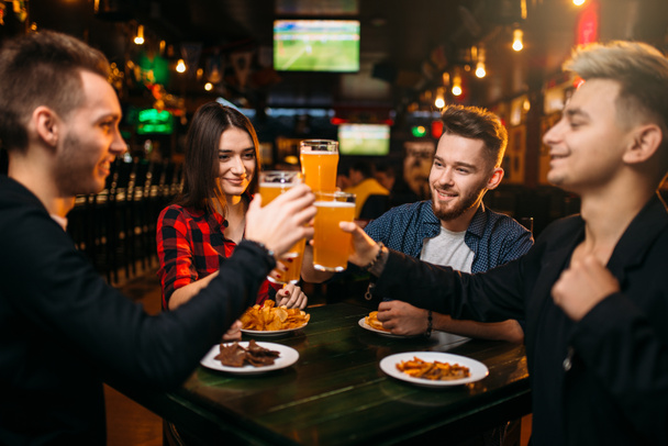 fröhliche Gesellschaft von Freunden hob ihre Gläser mit Bier in der Sportbar, Freizeit der Fußballfans - Foto, Bild